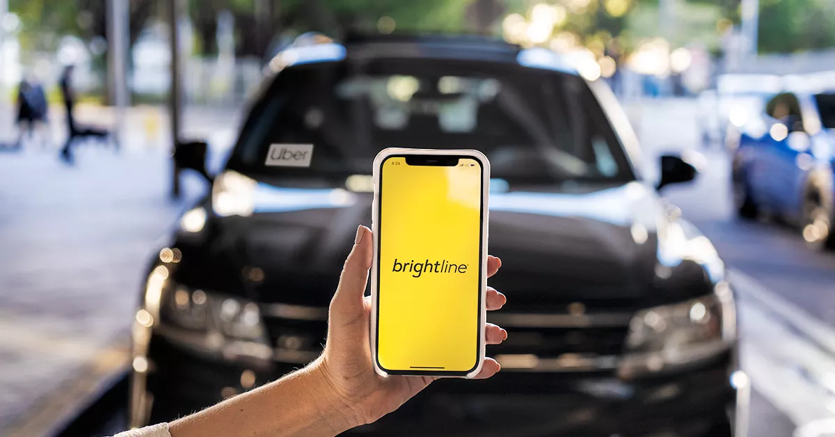 iphone with brightline app and car in background